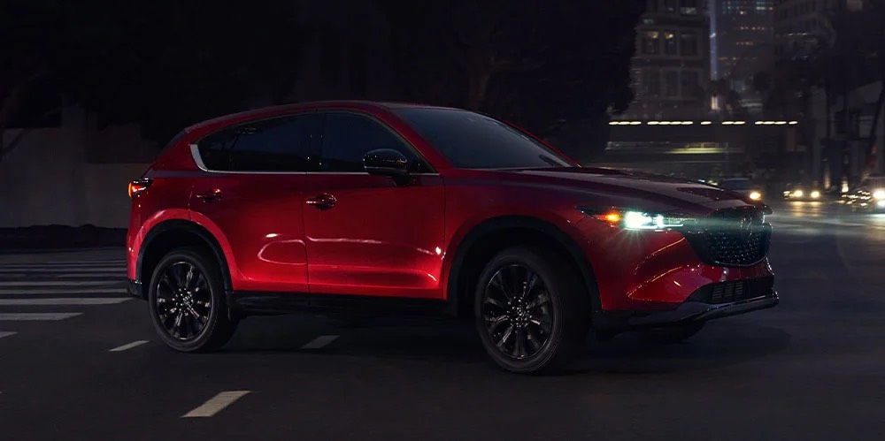 Vue latérale du Mazda CX-5 2023 tournant sur un intersection en ville.