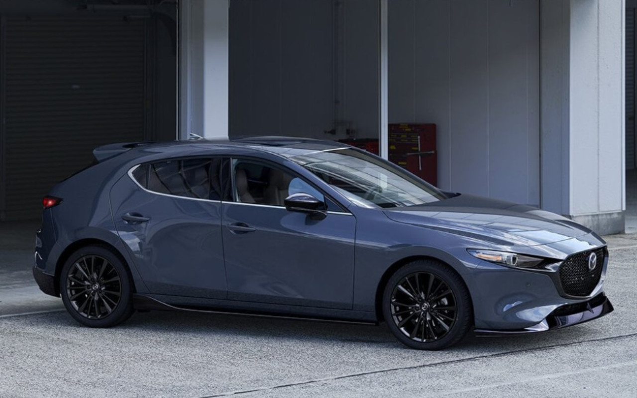 vue latérale avant d'une Mazda 3 Sport 2023 devant un garage