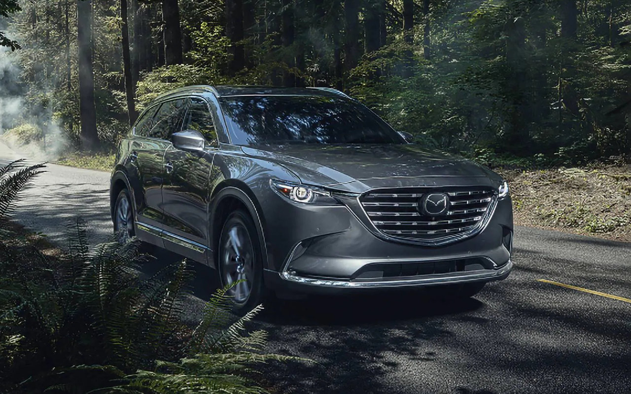 vue latérale avant d'une Mazda CX-9 sur une route en forêt