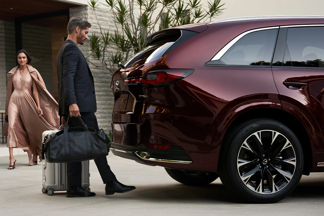 Vue arrière du Mazda CX-90 avec un couple chargant des valises