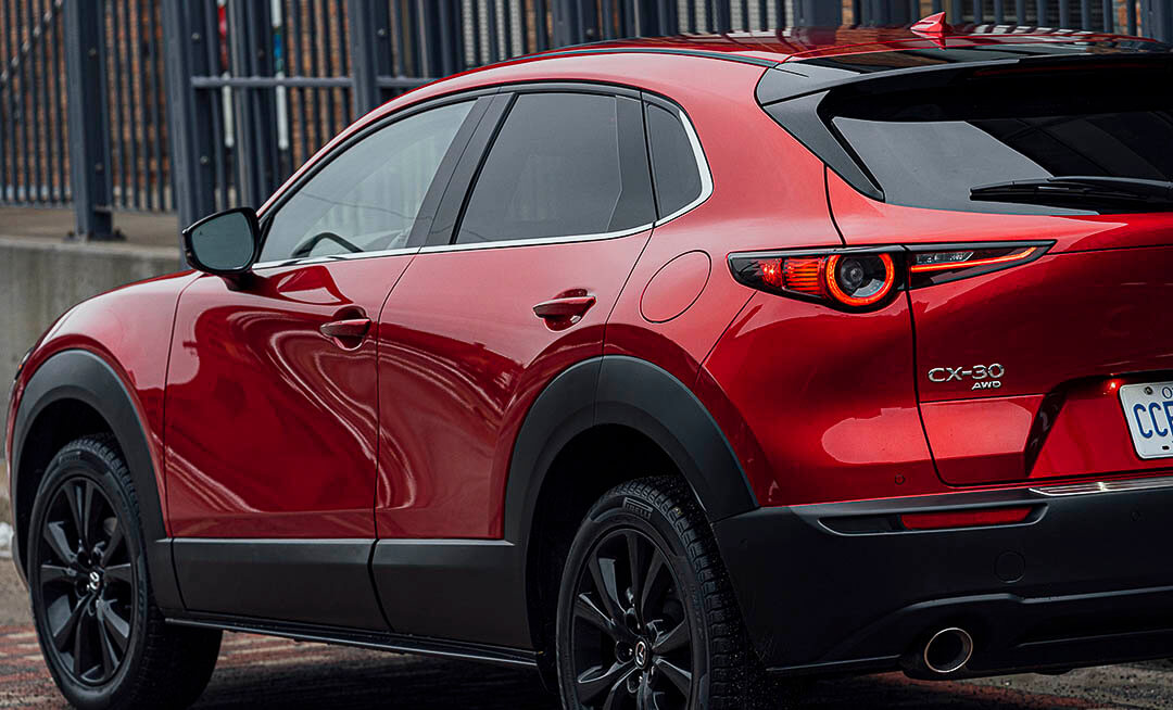 Vue 3/4 arrière d'un VUS Mazda CX-30 2021 rouge avec les lettres CX-30 AWD