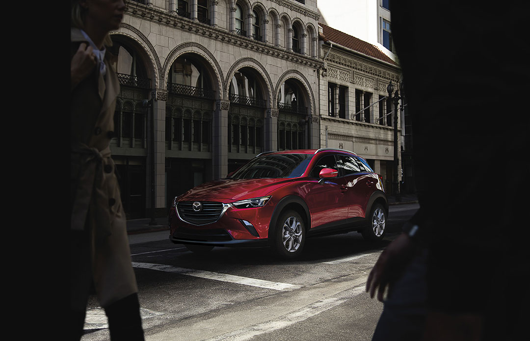 Vue 3/4 avant d'un VUS Mazda CX-3 Sport 2021 rouge garé en ville