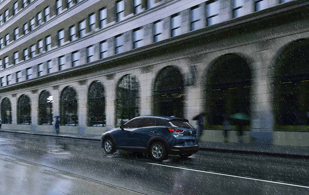 vue trois quart arrière du Mazda CX-3 2021 roulant sous la pluie