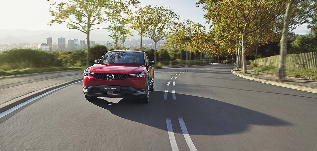 Le Mazda MX-30 2022 rouge effectuant un virage en douceur sur la route