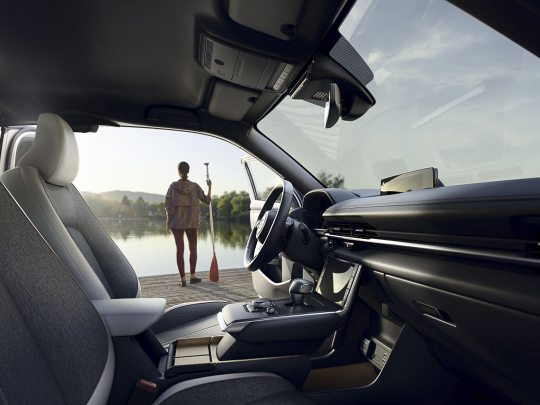 L'intérieur avant du Mazda MX-30 2022 incluant son tableau de bord avec la porte ouverte du conducteur