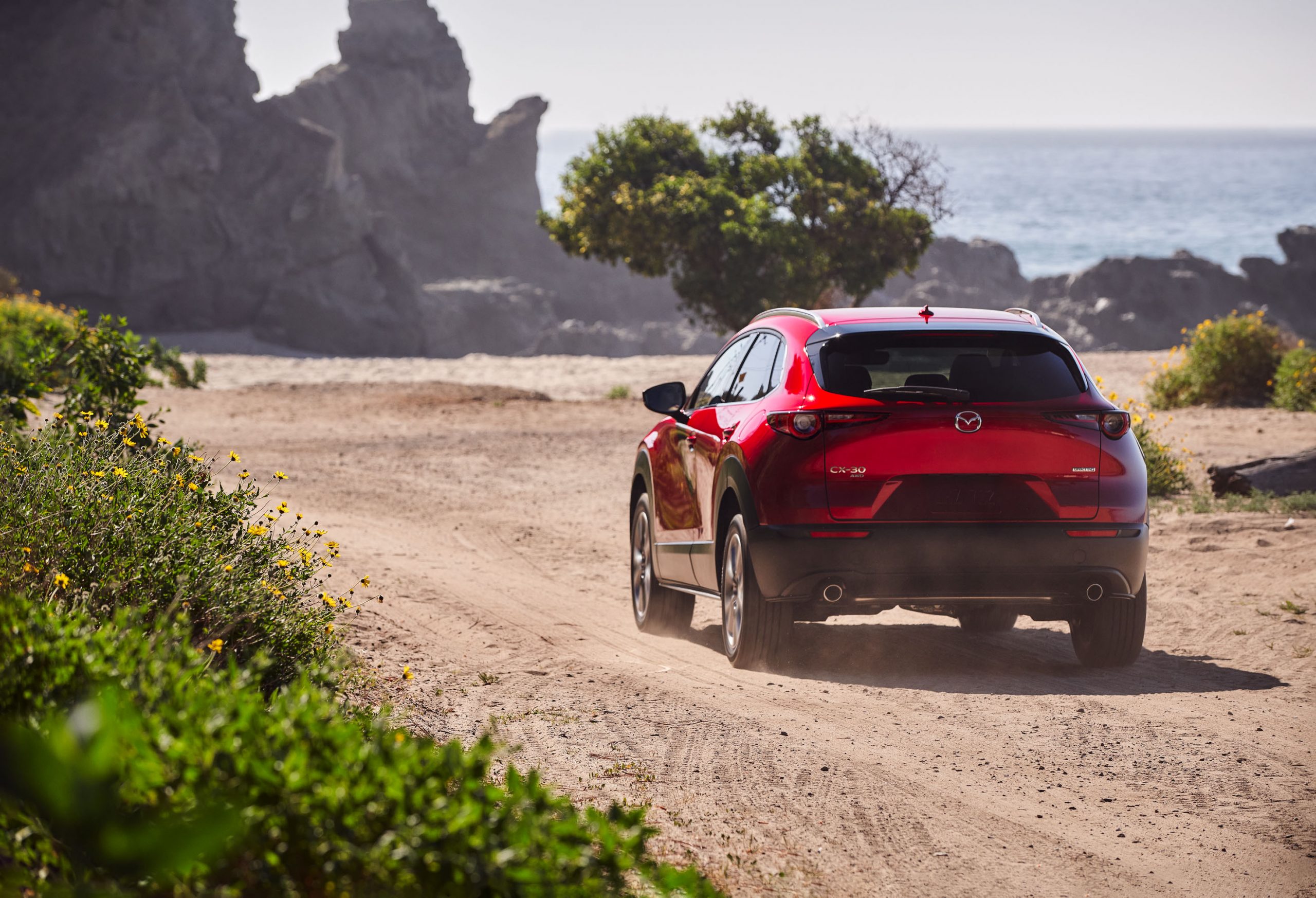 Mazda CX-30 2020 roulant sur un chemin de sable à proximité de l'océan