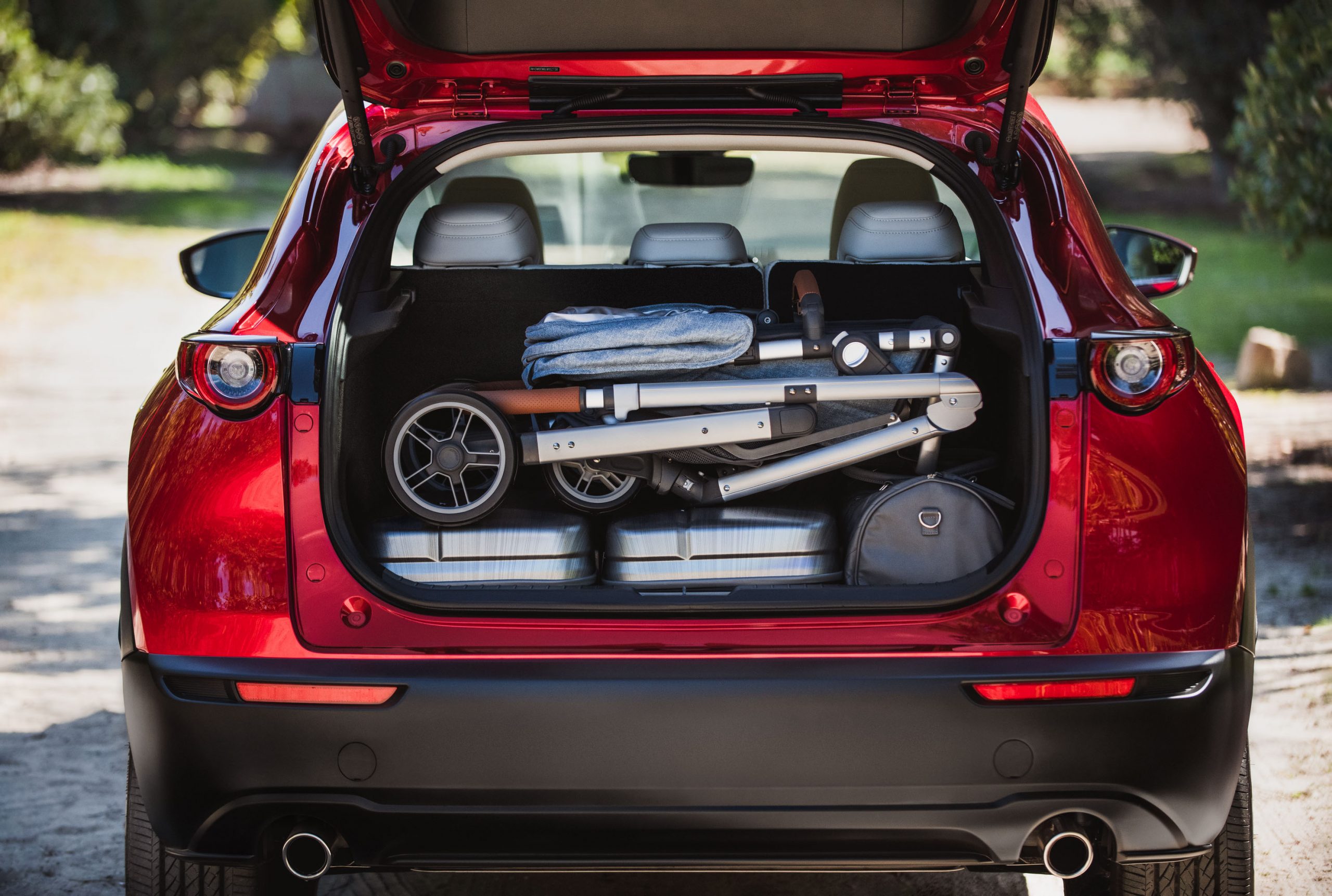 poussette de bébé pliée et bien rangée avec valise en-dessous dans le coffre du Mazda CX-30 2020